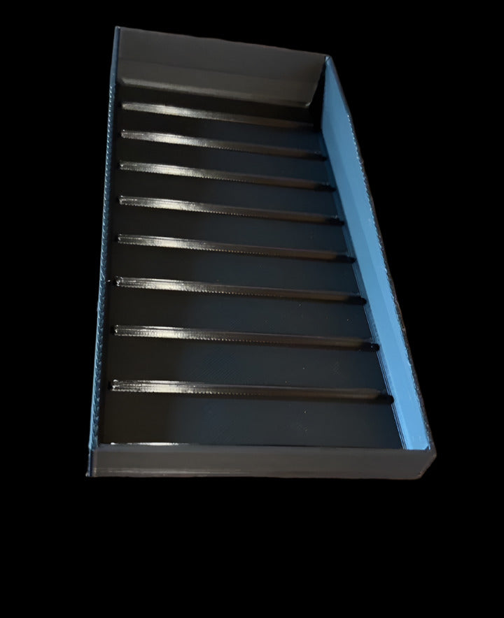 Black rectangular object with slotted design on a wooden surface