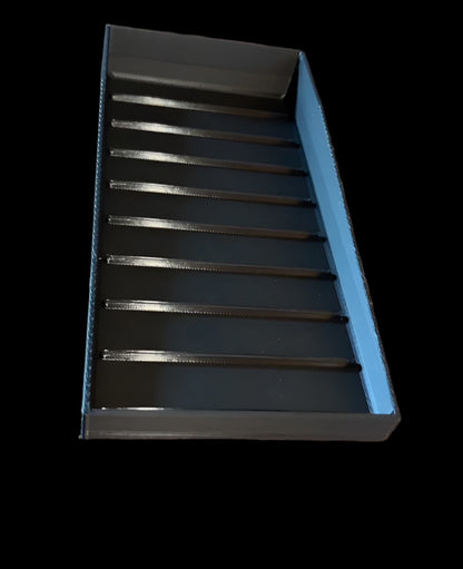 Black rectangular object with slotted design on a wooden surface